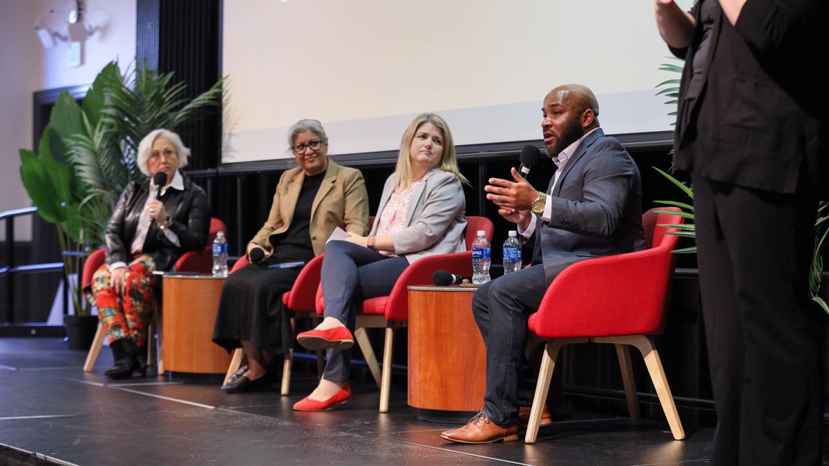 Four panelists speak on stage at the Maryland Student Affairs Conference.